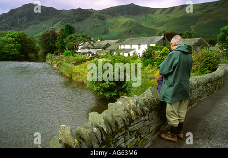 Cumbria Grange Borrowdale uomo sul ponte che si affaccia sul fiume Derwent Foto Stock