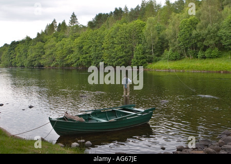 Fly Fisherman in waders con ghillies barca ormeggiata, trasporto rete di atterraggio, guado nel fiume Spey, Speyside, Castle Grant Beat, Scozia Regno Unito Foto Stock