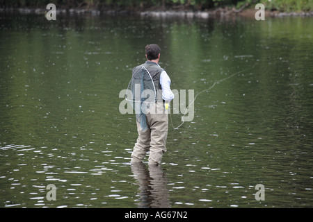 Fly Fisherman in waders, trasporto rete di atterraggio, wading lungo il fiume Spey, Speyside, Castle Grant Beat, Scottish Highlands, Scozia regno unito Foto Stock