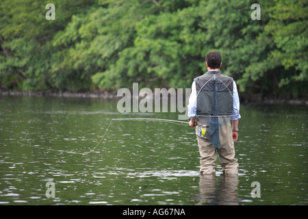 Pescatore a mosca in waders, portando landing net, il guado del fiume Spey, Speyside, il castello di concedere beat, Scotland Regno Unito Foto Stock