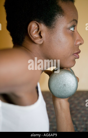 Atletica femmina nero pose tenendo i pesi Foto Stock