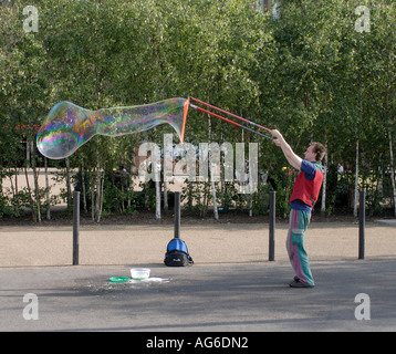 Un esecutore di strada gigante soffia bolle di sapone con colori Arcobaleno al di fuori della nuova Tate Gallery Southwark Londra Regno Unito 23 Giugno 2006 Foto Stock