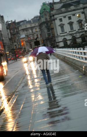 La singola persona a piedi ponte di Waterloo a Londra sotto la pioggia Foto Stock