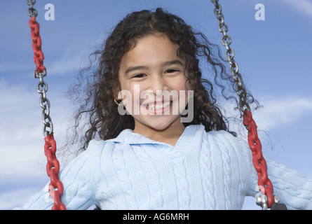 Felice di nove anni ragazza ispanica per rotazione all aperto con cielo blu in background Foto Stock