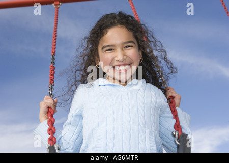 Felice ragazza ispanica oscillante con cielo blu, smile sorridente parco giochi all'esterno aria pulita Foto Stock