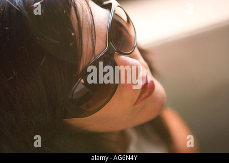 Elevato angolo di visione donna con occhiali da sole giovani cool closeup faccia indoor Foto Stock