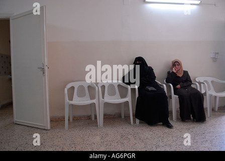 Velata dei profughi iracheni donna che indossa tutto nero Niqab indumento in attesa di assistenza medica in Amman Giordania Foto Stock