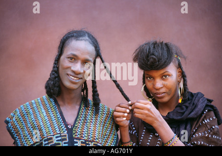 Il Niger nei pressi di Agadez donna fare tress in capelli uomo persone da tribù Wodaabe Foto Stock
