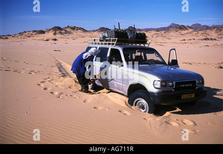 Il Niger nei pressi di Agadez uomo della tribù Tuareg in piedi da 4x4 vettura bloccato in sabbia Foto Stock