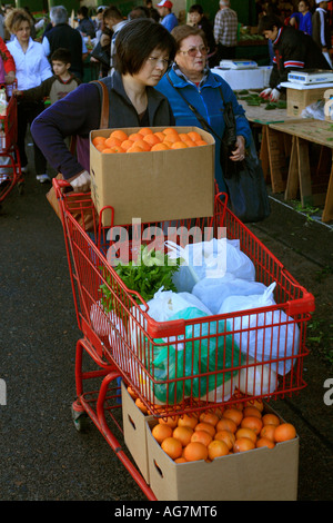 Una donna asiatica ruote di un carrello della frutta e della verdura come ella negozi a Flemington mercati in Sydney Australia Foto Stock