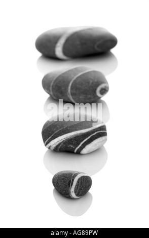 Quattro pietre con varie dimensioni in DOF isolato su uno sfondo bianco Foto Stock