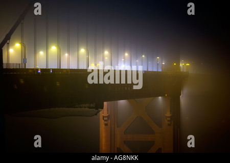 Il Golden Gate Bridge immerso nella nebbia di notte accese dalle luci della strada e del traffico Foto Stock