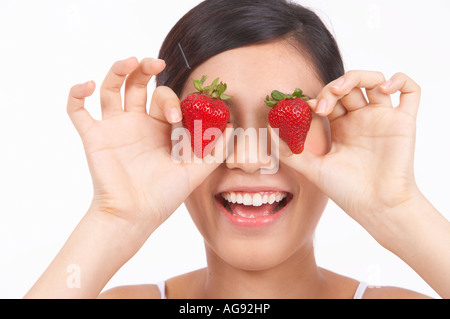 Ritratto di naturale giovane ragazza con due fragole sugli occhi Foto Stock