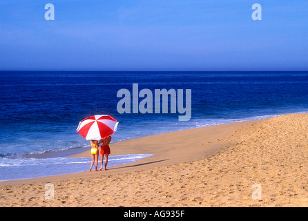 Giovane camminando lungo la spiaggia sotto il grande ombrello in Cabo San Lucas Messico Modello rilasciato image Foto Stock