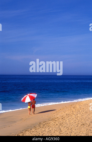 Giovane camminando sulla spiaggia sotto il grande ombrello in Cabo San Lucas Messico Modello rilasciato image Foto Stock