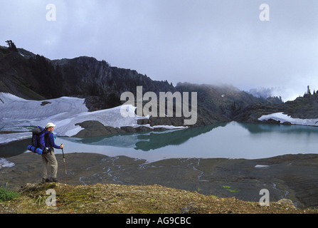 Escursionista affacciato sul lago alpino e prati North Cascades Cascade Mountains Washington Foto Stock