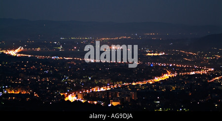 Le luci di strada su una autostrada crea una forma S attraverso una zona urbana di notte Foto Stock