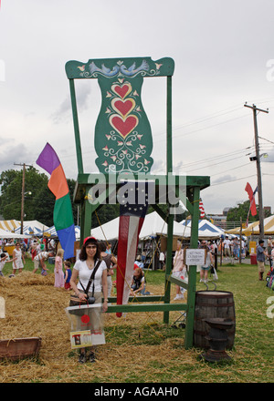 Donna asiatica sorge nella parte anteriore del gigante verde sedia a Kutztown Folk Festival Foto Stock