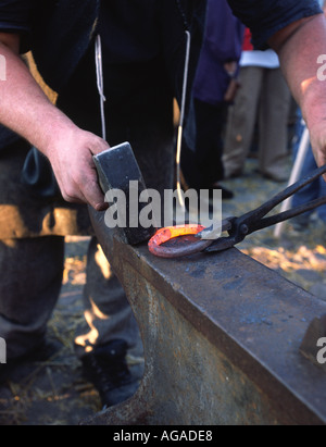 Fabbro forgiare un anello di ferro su una incudine Foto Stock