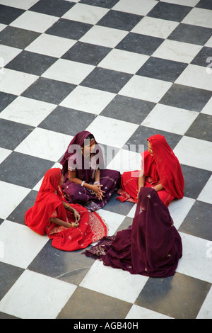 Le donne indiane in sari tradizionale seduta sul pavimento a scacchi del pavone città cortile complesso palazzo Udaipur India Foto Stock