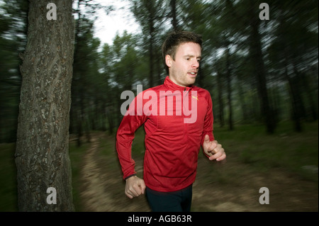 Runner maschio sul sentiero forestale Foto Stock
