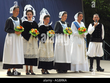 Cinque giovani donne in classic Breton costumi sono introdotti in una summer festival di folklore in Cornovaglia bretone Foto Stock