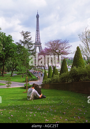 Giovane seduto su un prato a Trocadero vicino al Palais de Chaillot a Parigi con la Torre Eiffel Foto Stock