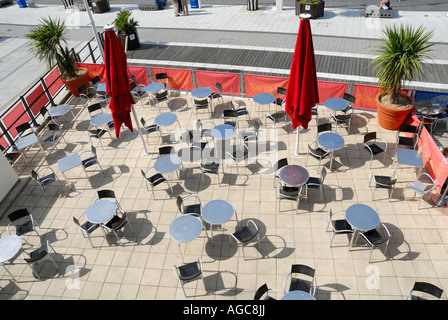 Modello di vuoto ristorante tavoli sotto la luce diretta del sole dal di sopra con rosso chiuso ombrelloni Foto Stock