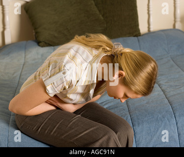 Giovane donna vivendo il dolore addominale. Potrebbe essere mensile dolori, intossicazione alimentare o mal di stomaco. Foto Stock