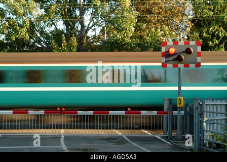 I binari ferroviari rosso lampeggiante spia livello di segno attraversando i cancelli di barriera stradale del paese treni passeggeri motion blur a Margaretting Essex England Regno Unito Foto Stock