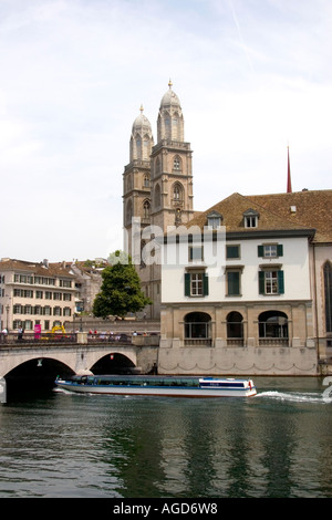 Tour in barca passa sotto il Munster ponte che attraversa il fiume Limmat a Zurigo, Svizzera con le torri della chiesa Grossmunster. Foto Stock