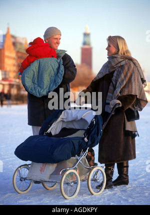 Famiglia spingendo baby carrello attraverso congelati Riddarfjärden, una baia del Lago Mälaren, con il Municipio di Stoccolma in inverno Foto Stock