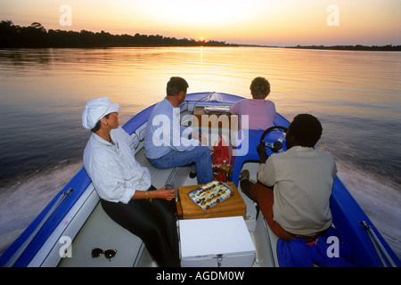 I turisti avente sunset tour in barca sulle acque vetroso del fiume Zambesi tra lo Zimbabwe e Zambia Foto Stock