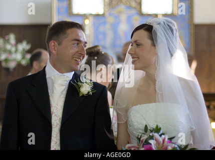 Sposa e lo sposo a piedi fino la corsia in un inglese chiesa parrocchiale Foto Stock