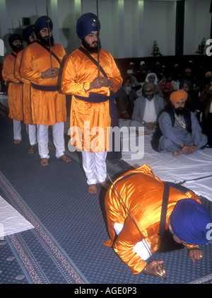 La religione sikh uomini che rappresentano il ' cinque santi' inginocchiarsi davanti al Guru Granth Sahib su Khalsa giorno Foto Stock