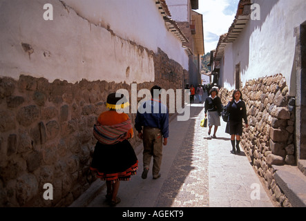 La gente peruviana oltrepassando pietre Inca alla base della parete lungo Calle Ahuacpinta nella città capitale di Cuzco, Cuzco, Provincia di Cuzco, Perù, Sud America Foto Stock