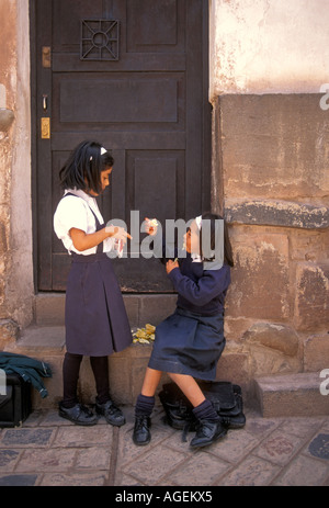 2, due peruviani, ragazze peruviano, scolare e scolari, indossano uniformi scolastiche, mangiando snack, Calle Ahuacpinta, Cuzco, Perù, Sud America Foto Stock