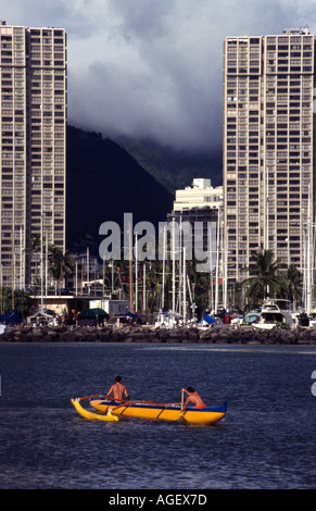 Alta scuola di canoa outrigger team pratica all'entrata di Ala Wai Canal con una tempesta costruzione sulle colline Foto Stock