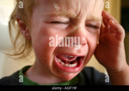 Close up bambino piangere, un anno di età con la mano sulla testa, avente una temper tantrum Foto Stock