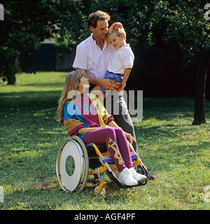 Donna disabile in carrozzina con l uomo e bambino in giardino Foto Stock