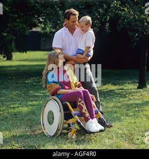 Donna disabile in carrozzina con l uomo e bambino in giardino Foto Stock