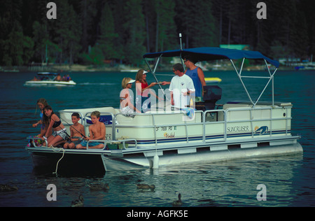 Due famiglie di godere di una giornata di navigazione adulti stanno parlando e mangiare e i bambini sono seduti sul retro della barca da pesca Foto Stock