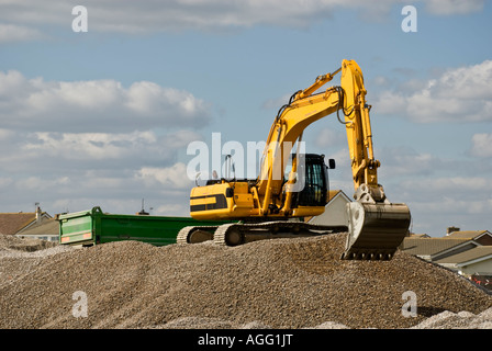 Escavatore giallo spostando le scandole in autocarro verde lavorando sulla spiaggia "moto-pala' Foto Stock