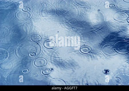 Le gocce di pioggia che colpisce la superficie di acqua e la creazione di increspature Foto Stock