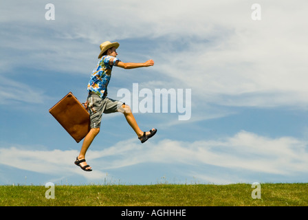 Un giovane uomo con la valigia in vacanza vestiti jumping contro il cielo blu Foto Stock