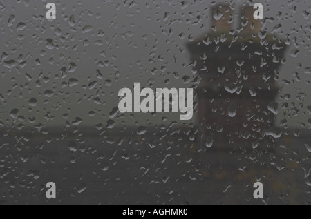 Una giornata invernale nebbiosa e piovosa che si affaccia da una finestra con case sullo sfondo Foto Stock