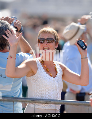 Uno spettatore in folla onde e sorrisi. Foto da Jim Holden. Foto Stock