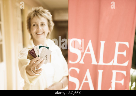 Donna matura che mostra le carte di credito e sorridente Foto Stock