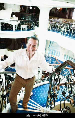 Metà uomo adulto il movimento verso l'alto su una scalinata e sorridente a bordo di una nave Foto Stock