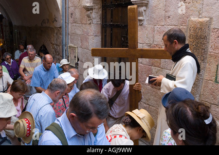 Israele Gerusalemme la città vecchia via crucis V stazione gruppo di pellegrini con una croce di legno kneeing in corrispondenza della stazione e la preghiera Foto Stock